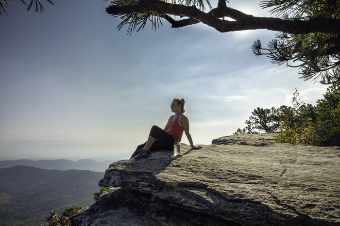 A person resting on a rock outcrop above the Blue Ridge Mountains