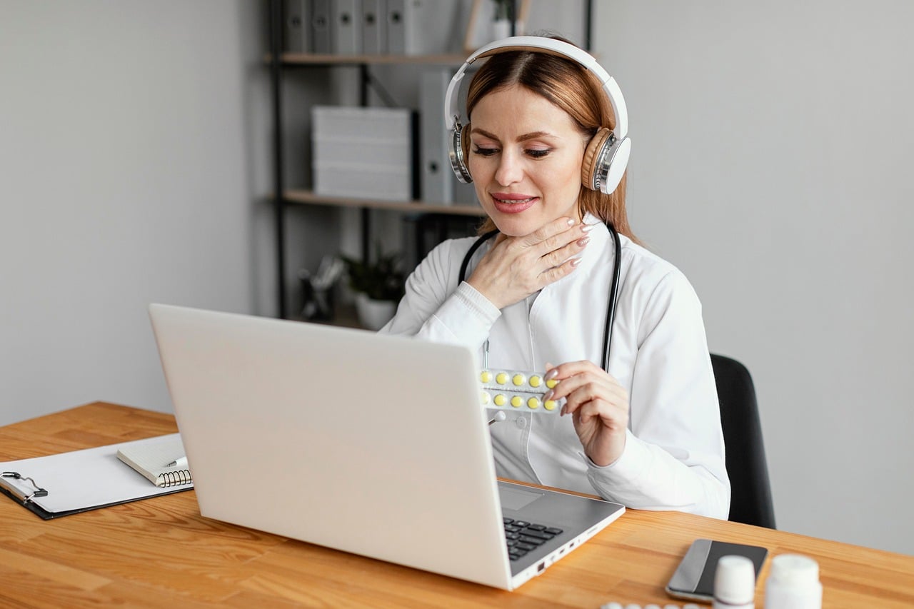 A clinician on a video call, touching her throat